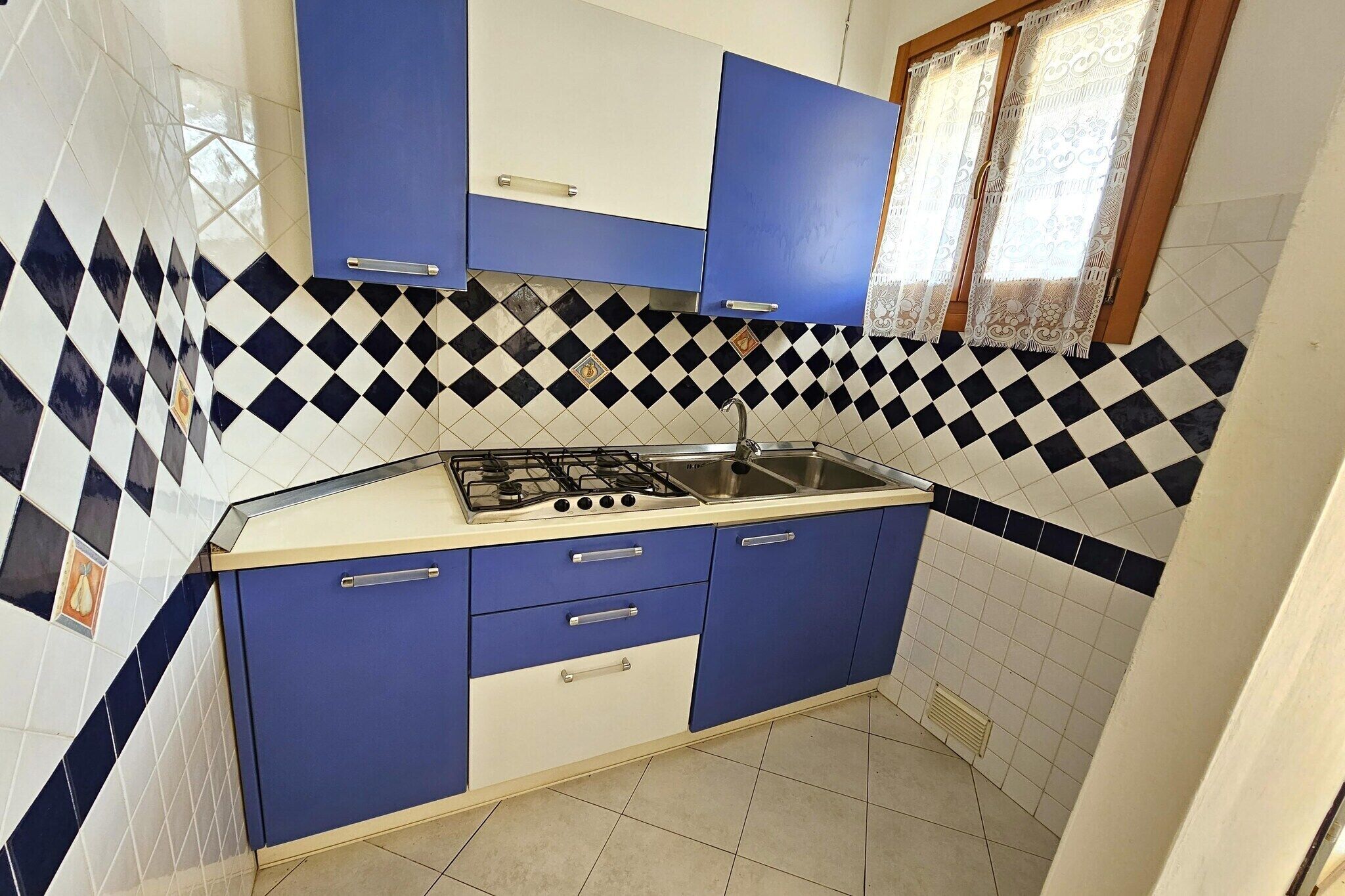 Une cuisine avec des armoires bleues et blanches, une cuisinière à gaz et un évier.