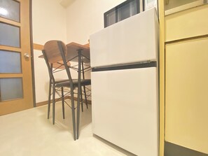 A kitchen with a white refrigerator, a wooden dining table, and two chairs. - 30sec walk to Tsutenkaku/1 stop to Namba Sta./AH55 (Ebisu Higashi Naniwa-Ward,Osaka City)