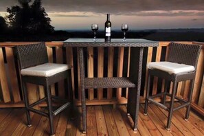 A wooden deck with two wicker chairs and a table, each with a wine glass and a bottle of wine. - Apartments Pepe's View - D (Bajío)