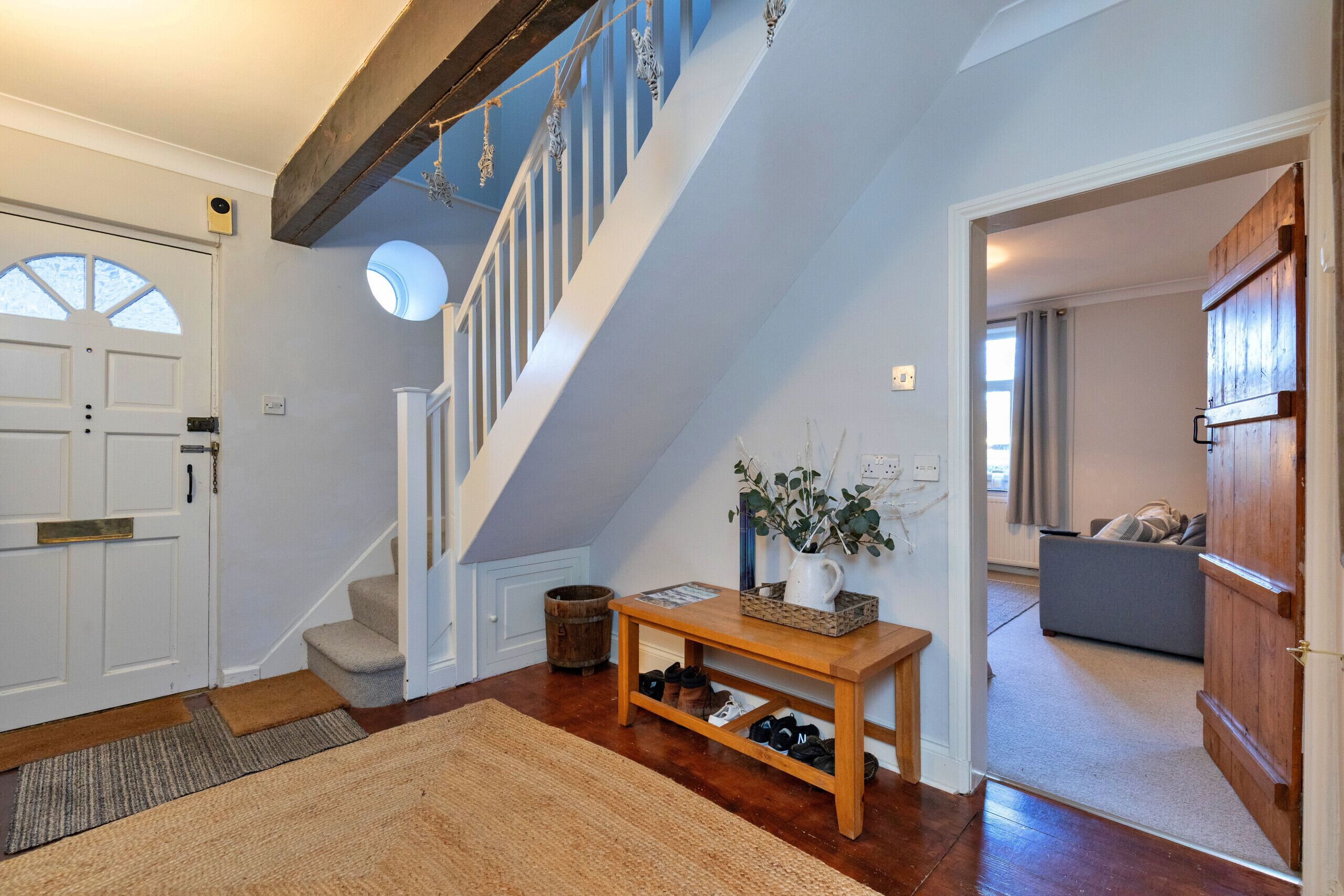 A staircase with a wooden finish and a white railing, leading to a second floor.