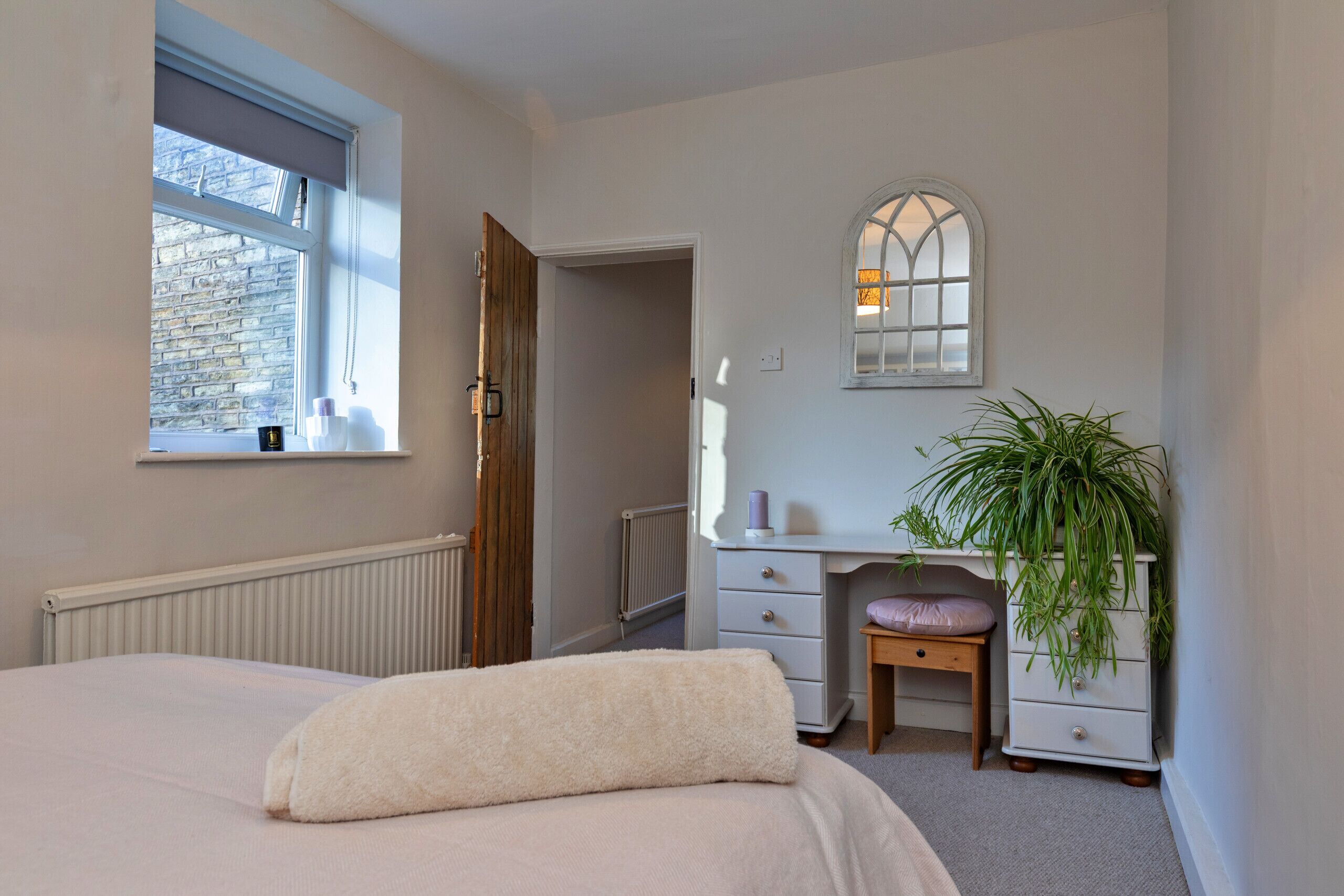 A bedroom with a bed, a dresser, a window, and a radiator.