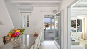 A modern, well-lit room with a marble countertop, a vase of flowers, and a view of a pool and outdoor area. - My Rental Homes - Villa Cassandra, less than 2 km from the beach with pool (Mykonos)
