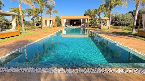 Uma piscina retangular com água azul cristalina, delimitada por uma borda de pedras.