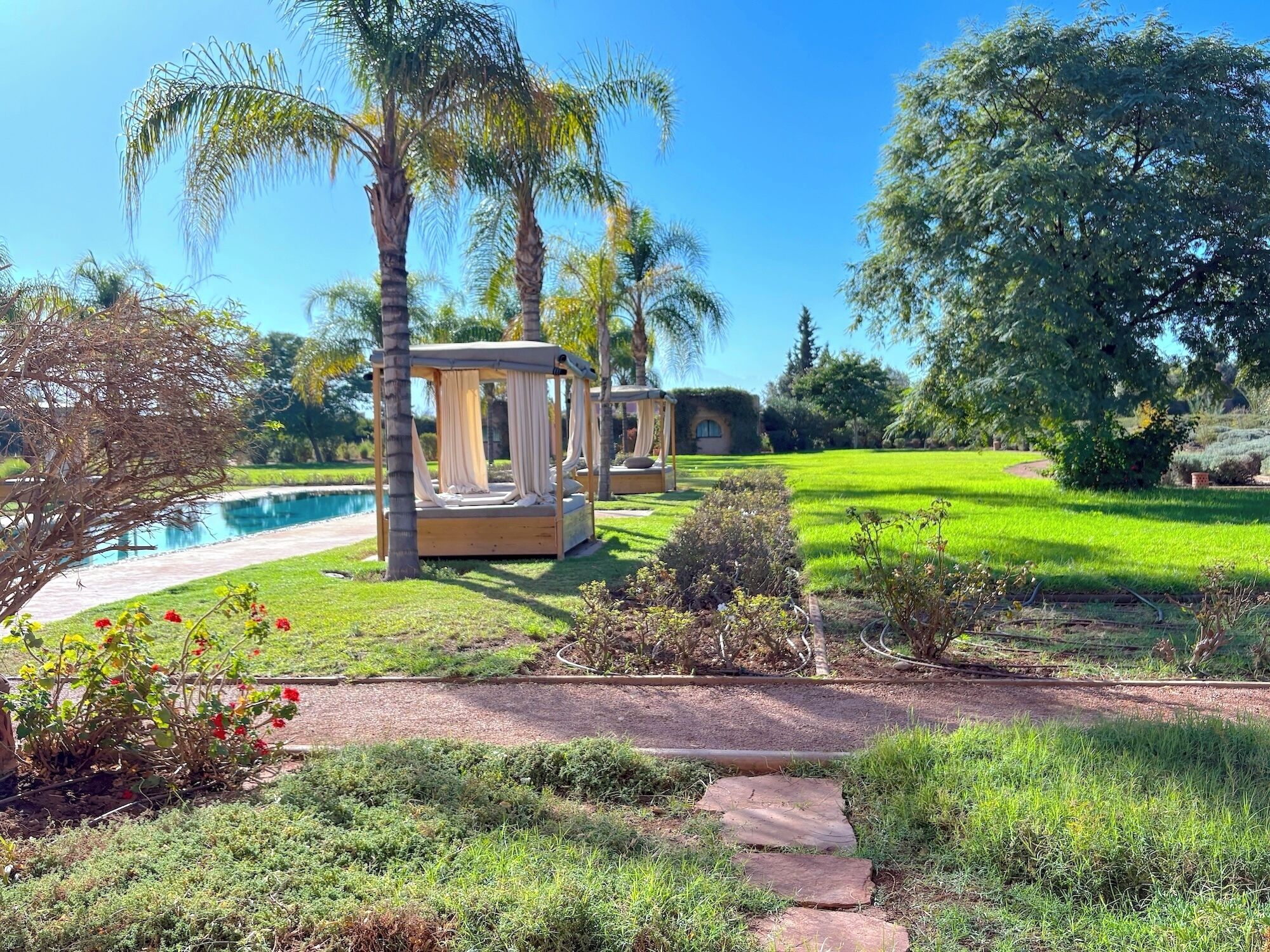 A garden with a wooden gazebo, a swimming pool, and a well-maintained lawn.