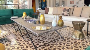 Uma sala de estar moderna com um sofá verde, um sofá branco e uma mesa de centro com objetos decorativos.