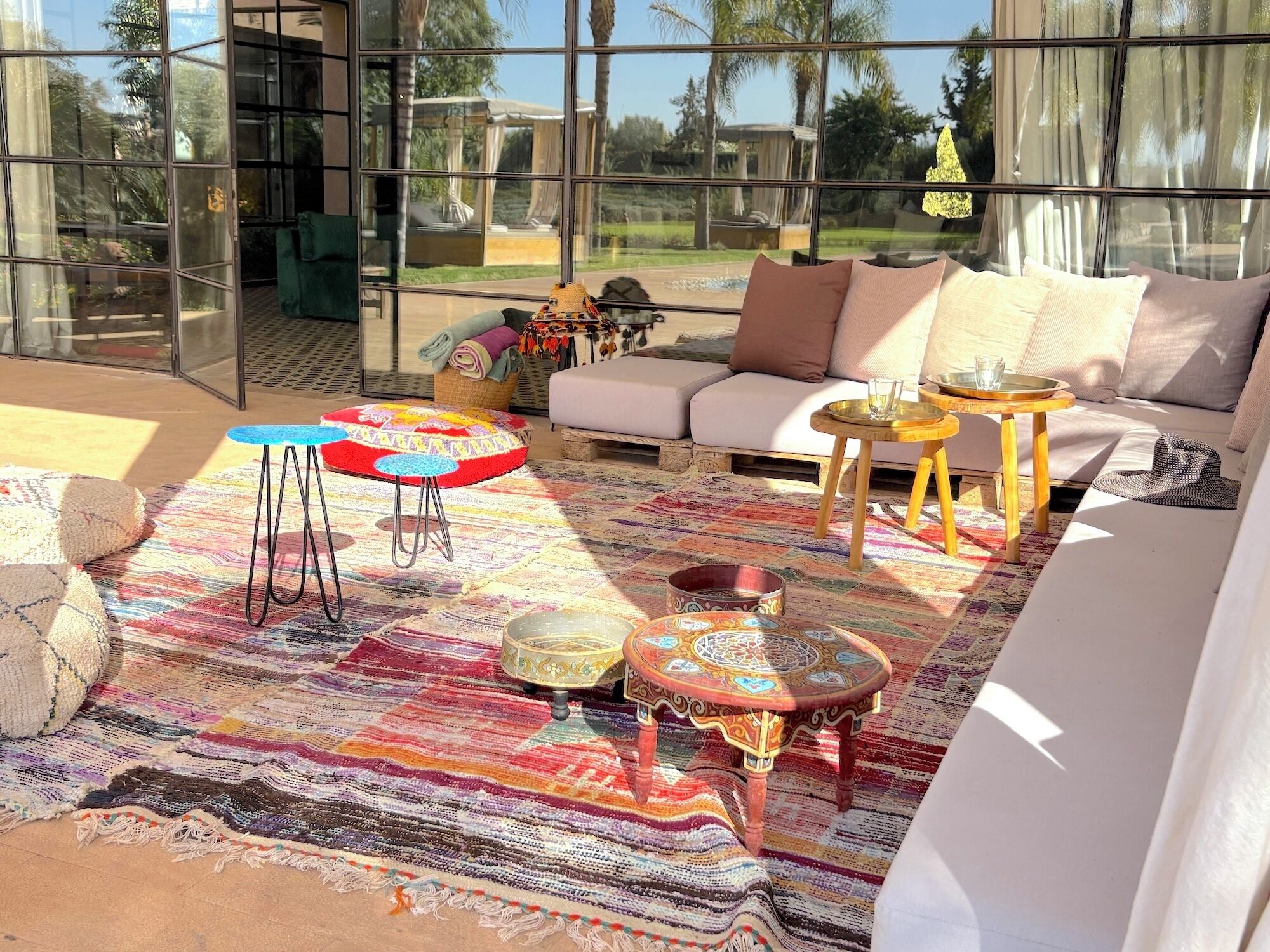 A modern living room with a glass wall, a colorful woven rug, a sofa, and a coffee table.