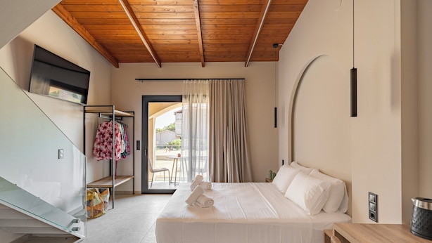 Quarto de hotel moderno com cama, teto de madeira, divisória de vidro e vista para o exterior.