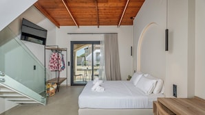 Quarto com cama, teto de madeira, porta de vidro para o exterior e uma pequena mesa.