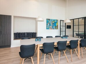 Uma sala de conferência com uma mesa comprida, cadeiras pretas e um quadro na parede.