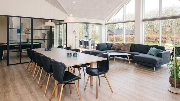 Un interior moderno con zona de comedor, sofá y grandes ventanales.