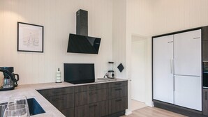 Una cocina moderna con horno empotrado, cafetera y licuadora sobre la encimera.