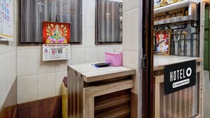 Zona de recepción de un hotel con un mostrador de madera, un calendario y un letrero con el nombre del hotel.