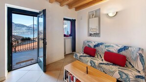 Un salon avec un canapé, une table basse, une vue à travers une porte vitrée et un radiateur.