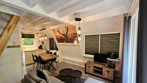 Ein moderner Loft-Wohnraum mit Essbereich, einer Couch, einem Fernseher und einem großen Fenster.