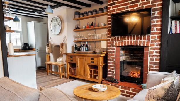 Un salon chaleureux avec une cheminée, des meubles en bois et un téléviseur fixé au mur en briques.