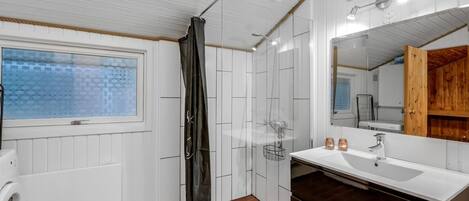 Un baño con ventana, ducha, lavabo y espejo.