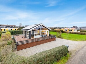 A modern house with a large glass window, a wooden deck, and a gravel driveway. - "Bundi" - 25m from the sea by Interhome (Hejls)