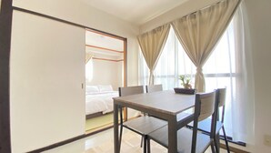 Ein Zimmer mit Bett, Esstisch und einem fensterbepflanzten Fenster.