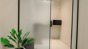 Une chambre moderne avec une porte-fenêtre coulissante, une plante en pot et un four à micro-ondes fixé au mur.