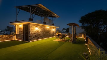 Eine Dachterrasse mit Backsteinwand, Sitzgelegenheiten im Freien und einem überdachten Bereich.