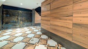 Un interior moderno con piso de diseño geométrico, panel de pared de madera y puerta metálica cerrada.