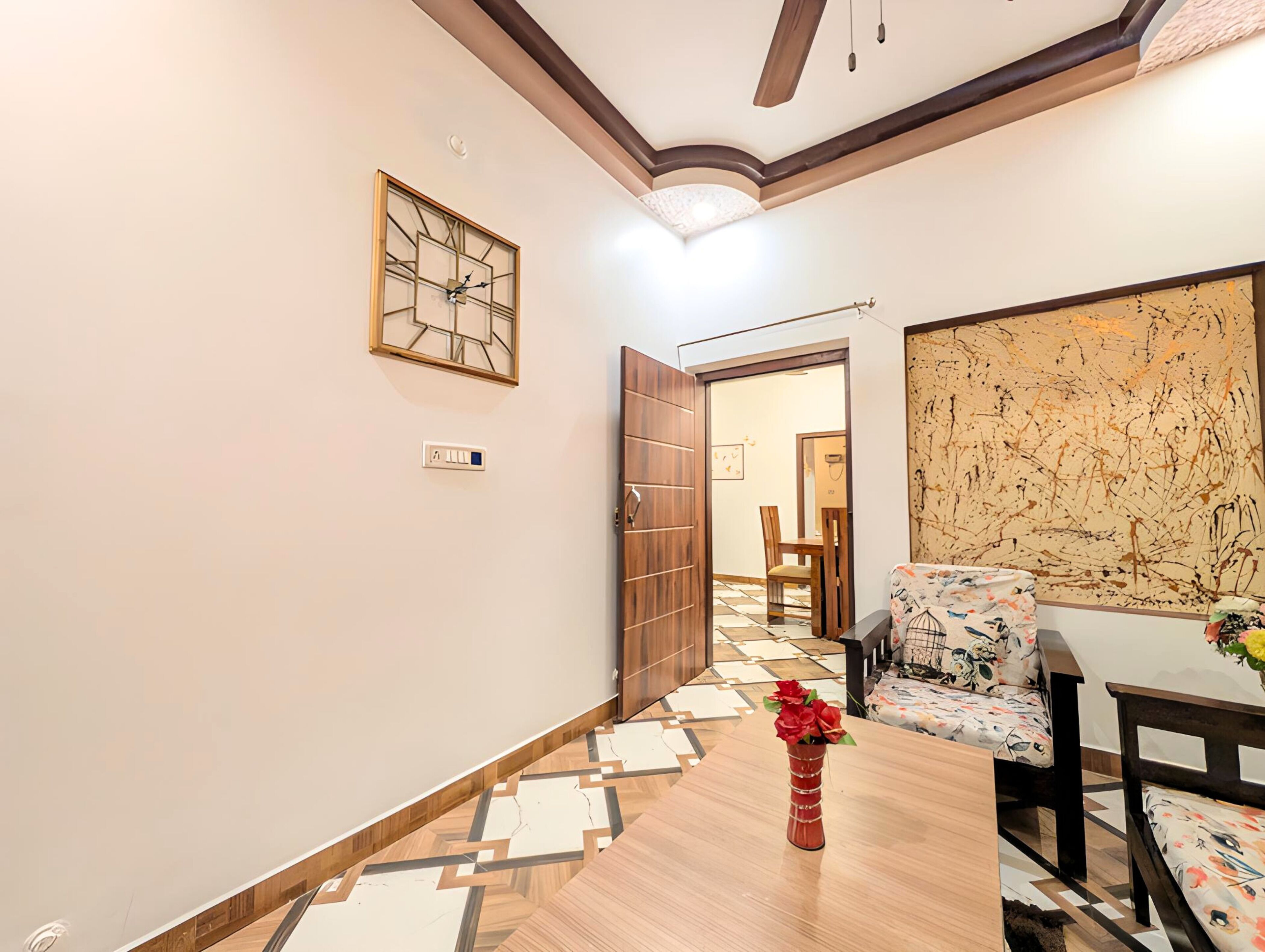 Un pasillo con piso de madera, un reloj en la pared y una puerta que da a un comedor.