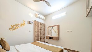 Habitación de hotel con cama, ventilador de techo, equipo de aire acondicionado, televisor montado en la pared y piso con diseño.