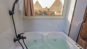 Eine Badewanne mit Blick auf die Pyramiden durch ein Fenster.