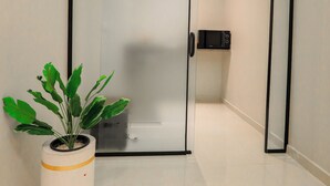 Ein modernes Zimmer mit einer Schiebeglastür, einem Blumentopf und einer Wand-Mikrowelle.