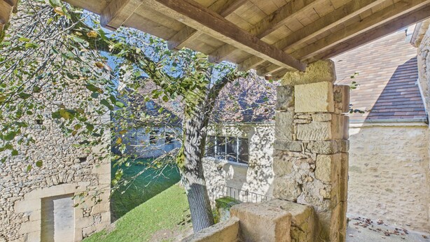 A stone staircase leading up to a covered area with a view of a building and a tree. - Valley View – Large house for 10 – Pool (Les Eyzies-de-Tayac-Sireuil)