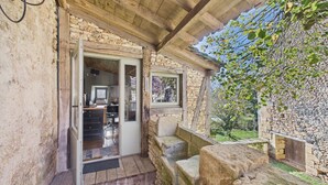 A stone building with a wooden ceiling and a glass door leading to a kitchen area. - Valley View – Large house for 10 – Pool (Les Eyzies-de-Tayac-Sireuil)