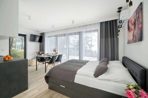 A modern bedroom with a large bed, a desk, and a dining area. - Cozy Studio in Karpacz | Parking, Garden, Air Conditioning (Karpacz)