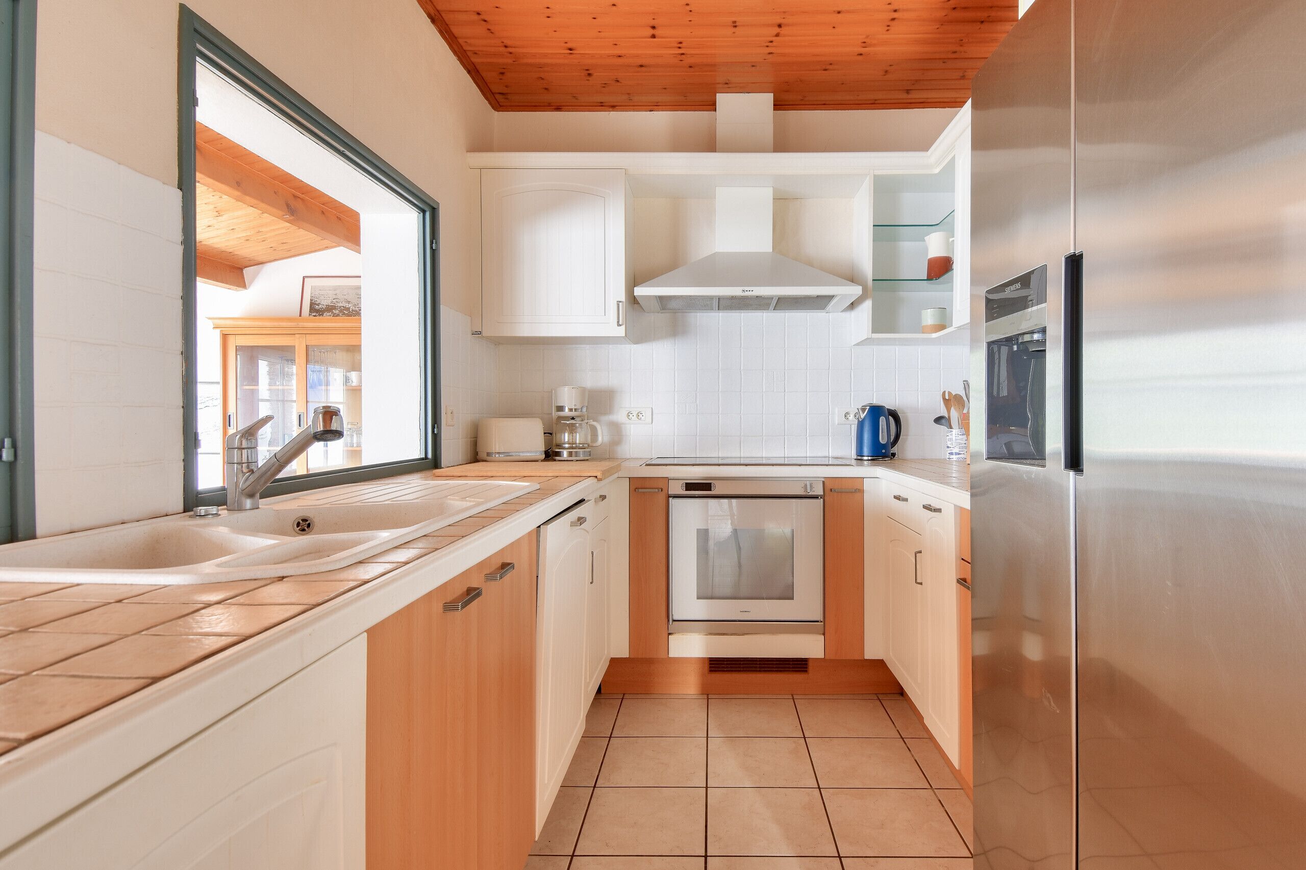 Una cucina moderna con mobili bianchi, un frigorifero in acciaio inossidabile e un forno integrato.