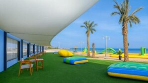 A covered outdoor area with artificial grass, seating, and inflatable play structures. - Single Room with Sea View – Aquatic Village, Red Sea Resort (Red Sea Governorate)