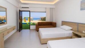 A hotel room with a bed, a sofa, a desk, and a view of the beach. - Single Room with Sea View – Aquatic Village, Red Sea Resort (Red Sea Governorate)