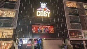 Un immeuble à plusieurs étages dont la façade est ornée d’une grande enseigne indiquant le mot « COSY ».