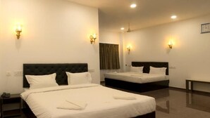 Une chambre d’hôtel avec deux lits, une table de chevet, un banc et des appliques murales.