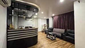 Un salon moderne avec un canapé noir aux lignes courbes, un fauteuil à motifs et un plancher en bois.