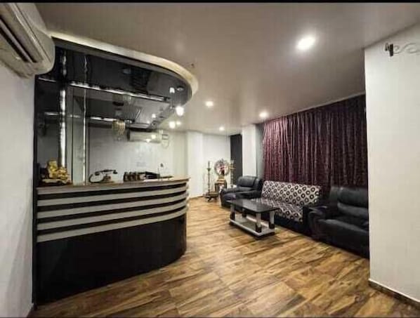 Una sala de estar moderna con un sofá negro curvo, un sillón estampado y piso de madera.