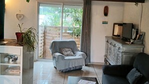 A living room with a sofa, a chair, a television, and a cabinet. - Loft ambrussum (Lunel)