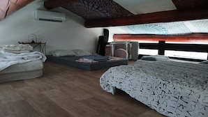 A bedroom with a loft bed, a small sofa, a bedside table, and a window with a view. - Loft ambrussum (Lunel)
