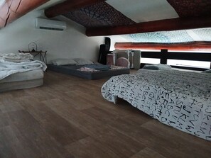 Una camera da letto con letto a soppalco, un piccolo divano, un comodino e una finestra vista.