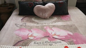 A bed with a floral duvet cover, a heart-shaped pillow, and a card with a message. - Loft ambrussum (Lunel)