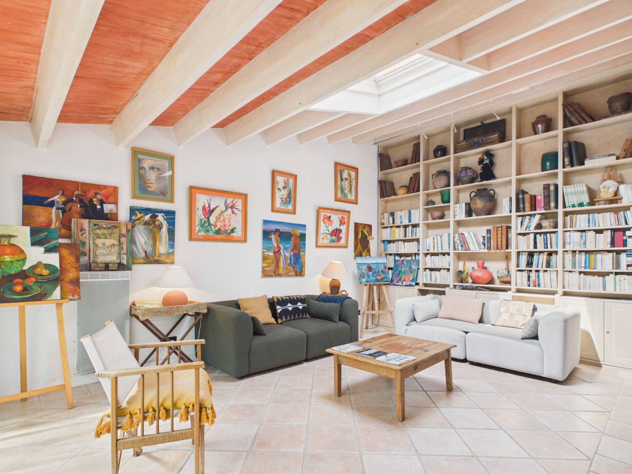 A living room with a sofa, coffee table, and paintings on the wall.