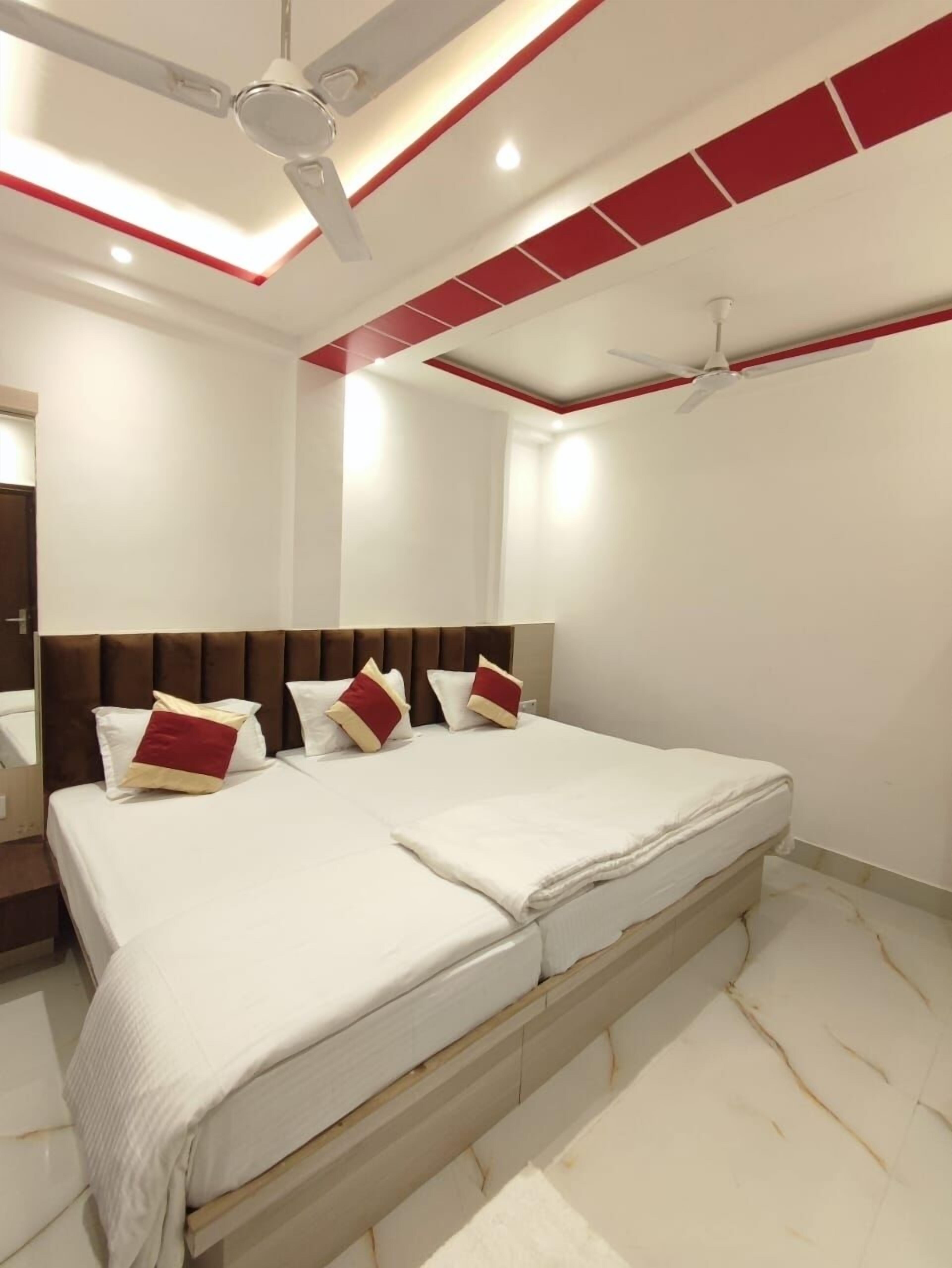A modern bedroom with a large bed, two ceiling fans, and a red and white color scheme.