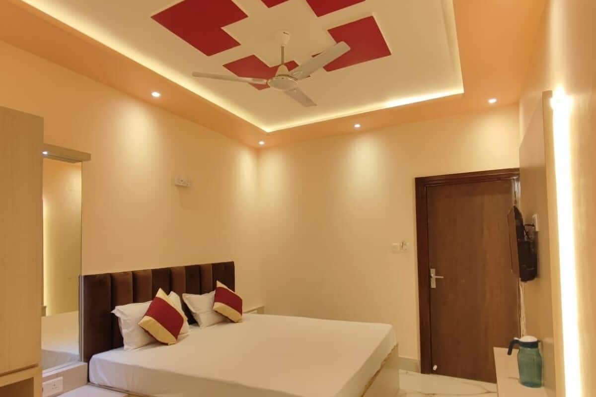 A modern bedroom with a bed, a ceiling fan, and a wooden door.