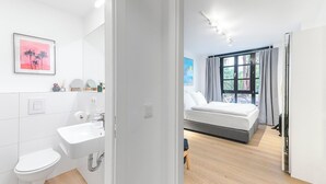 A modern hotel room with a bathroom, a bed, and a large window. - 2-room apartment in Charlottenburg-Wilmersdorf (Berlin)