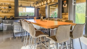 A modern kitchen with a wooden interior, a large dining table, and bar stools.