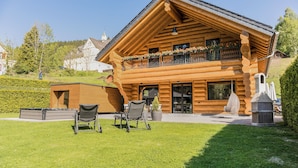 A log cabin with a balcony, outdoor seating, and a well-maintained lawn. - Vacation log cabin Schwarzwald 1 - Luxury chalet with sauna & whirlpool on the Feldberg (Feldberg (Schwarzwald))