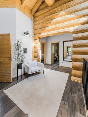 L’intérieur d’un chalet moderne en bois, avec un canapé blanc, une plante en pot et un plafond en bois.